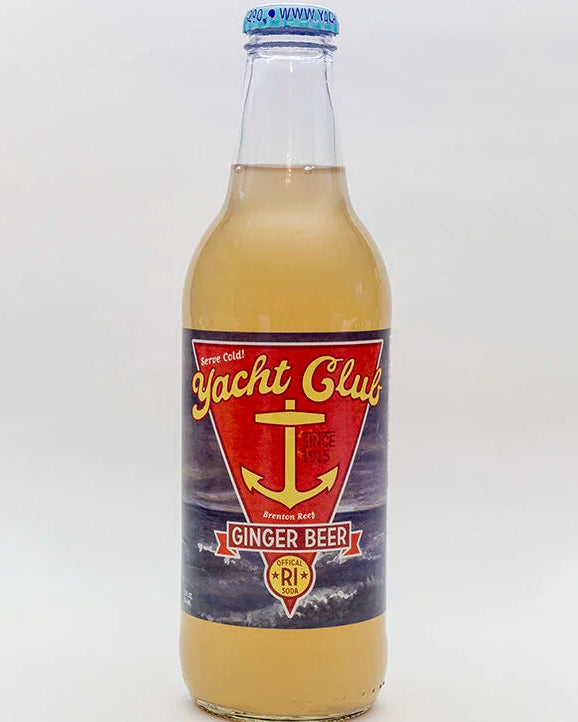 A glass bottle of Yacht Club Ginger Beer with a blue cap and a red, yellow, and navy label, shown on a light gray background.
